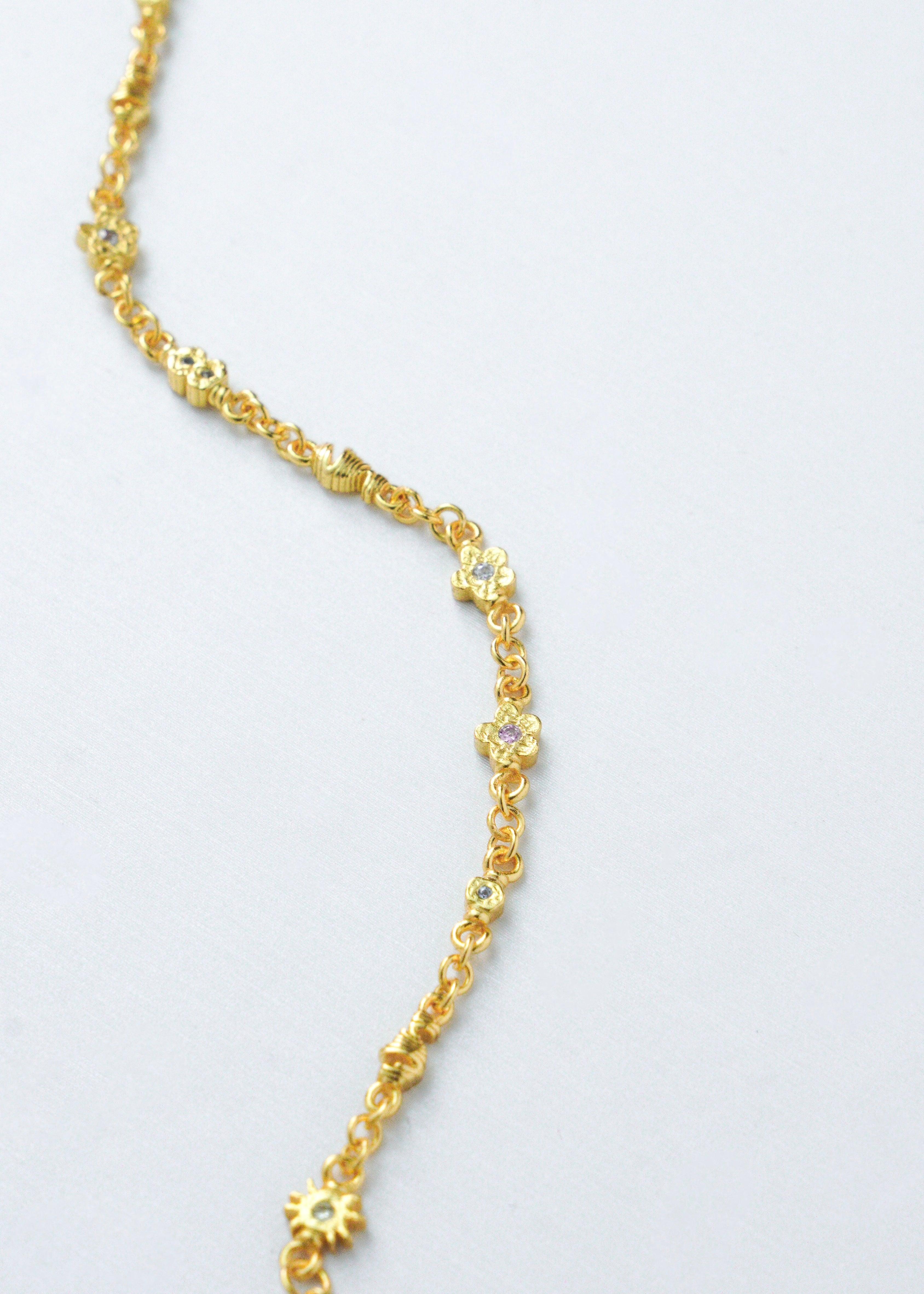 Et delikat gullarmbånd plassert på en hvit bakgrunn.