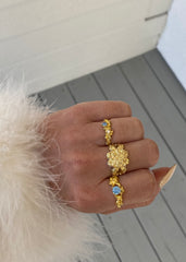 En kvinne i ført fuskepels poserer med hånden sin utsmykket med tre gullringer.