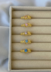 En kolleksjon av gullringer i ulike farger plassert delikat på et smykkebrett.