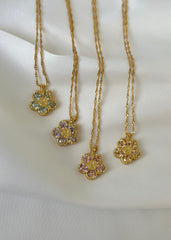 En samling gullblomsterkjeder med ulike fargede krystaller på en elegant hvit bakgrunn. 