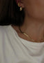 En kvinne har på seg Snake Chain halskjede i gull, i øret har hun Dome Hoops i gull og Pave Earcuff.
