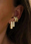Nærbilde av en kvinne sitt øre. Hun har på seg to Pave Earcuff, en med hvite glitrende zirconia stener og med oliven grønne glitrende stener. Kvinnen har også Diamond rectangle øredobber, en i Large og en i small. En trendy og stilig kombinasjon.