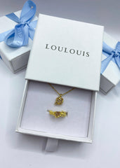 En delikat smykkeboks med en smykkekombinasjon av gullhalskjede og ring med matchende stener.