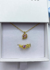 En smykkeboks med en matchende kombinasjon av ring og halskjede i gull med rosa stener.