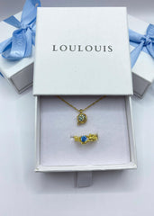 En elegant smykkeboks med matchende gullhalskjede og ring med blå stener. 