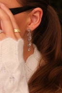 Nærbilde en elegant og stilfull dame med solbriller. I øret henger Daisy Flower i sølv med blå cubic zirconia stener.