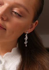 Nærbilde av en kvinne med Daisy Flower Earrings i sølv med hvite cubic zirconia stener.