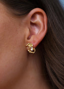 Nærbilde av sideprofilen til en kvinne med en elegant gulløredobb med champagne sten. 