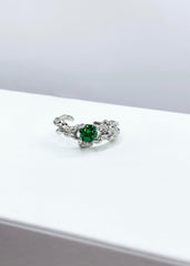 Vakker sølvring med smaragd grønn sten på en elegant hvit bakgrunn.