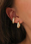 Nærbilde av et øre med Pave Earcuff med hvite glitrende zirconia stener og Dome hoops i gull. En delikat og stilfull kombinasjon.