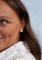 Profilbilde av kvinne iført hvit bluse og gulløreringer med lilla stener – hverdagsluksus