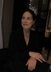 Kvinne med elegant sort hår og matchende mørk kjole poserer stil-fullt med sølvringer på hendene sine.