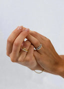 Hender iført ringer i gull og sølv pyntet med steiner, mot lys bakgrunn. Elegant og sofistikert smykkestil.