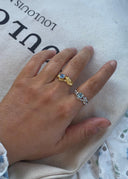 En hånd som lener seg over et bærenett i ført to ringer i gull og sølv med blå stener.