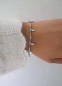 Et delikat håndledd med en hvit ull genser og et sølv armbånd med blå stener.