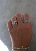 En delikat hånd med vakre sølvsmykker som inkluderer ringer og armbånd med blå stener. 