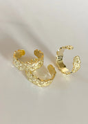 Tre StarWave ringer ligger stilfult på en hvit minimalistisk flate. Solen skinner på ringene så de glitrer.