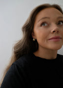 En kvinne med varm hudtone, brunt og langt hår i ført en sort genser. 