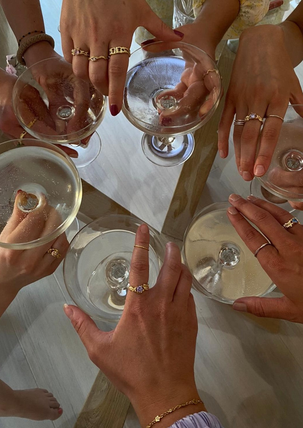 Flere hender former en "ring". Alle hendene har på seg flere forskjellige ringer fra Loulouis. Flere av hendene har på seg Melodie ringen med lavendel farget sten. En hånd bærer også stjernestøv armbåndet i fargen gull.