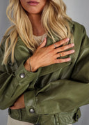 Bilde av en stilfull kvinne med oliven grønn vegansk skinnjakke og gullsmykker.