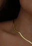Nærbilde av nakken til en kvinne som har på seg Snake Chain halskjede i gull. Halskjedet legger seg pent inntil halsen.