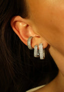 Nærbilde av en kvinne sitt øre i solen. Hun har på seg Pave Earcuff med hvite glitrende zirconia stener. Kvinnen har også Diamond rectangle øredobber, en i Large og en i small. En trendy og stilig kombinasjon.