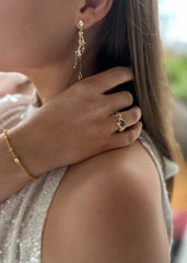 Elegant kvinne på fest med glitrende øredobber og matchende ring, delvis skulderbilde med sølvkjole for sofistikerte smykker.