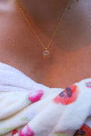 Nærbilde av en kvinne på en strand iført håndkle med Lykkesten halskjede i gull med rosa cubic zirconia.