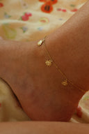 Nærbilde av Sunflower Anklet i gull. Små delikate solsikker henger rundt ankelkjedet og gir et rolig og sommerlig uttrykk.