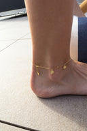 Nærbilde av ankelen til en kvinne. Kvinnen har på seg Sunflower ankelkjede i gull. Ankel kjedet har en forlenger som henger delikat ned på baksiden av kvinnen sin ankel. På forlengeren er det gravert en liten sommerfugl.
