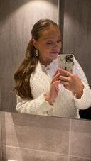 En kvinne tar selfie i speilet mens hun har på seg Daisy Flower øredobber og Star Wave ringer.