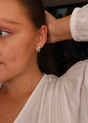 Nærbilde av en kvinne med melodie gull øredobb med rosa cubic zirconia sten.