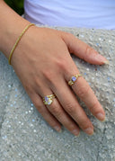 Nærbilde av en kvinnehånd med Melodie lavendel ring i gull, luna ring i lavendel og connection armbånd.